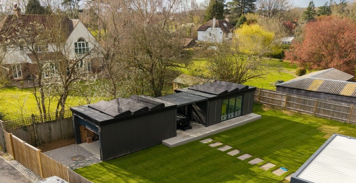 Aerial view of a black-clad insulated garden studio with solar panels and landscaped garden by Cruise Garden Rooms
